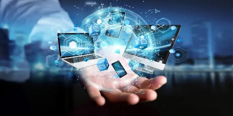 Businessman's hand with a holographic network connecting a laptop, monitor and smartphone
